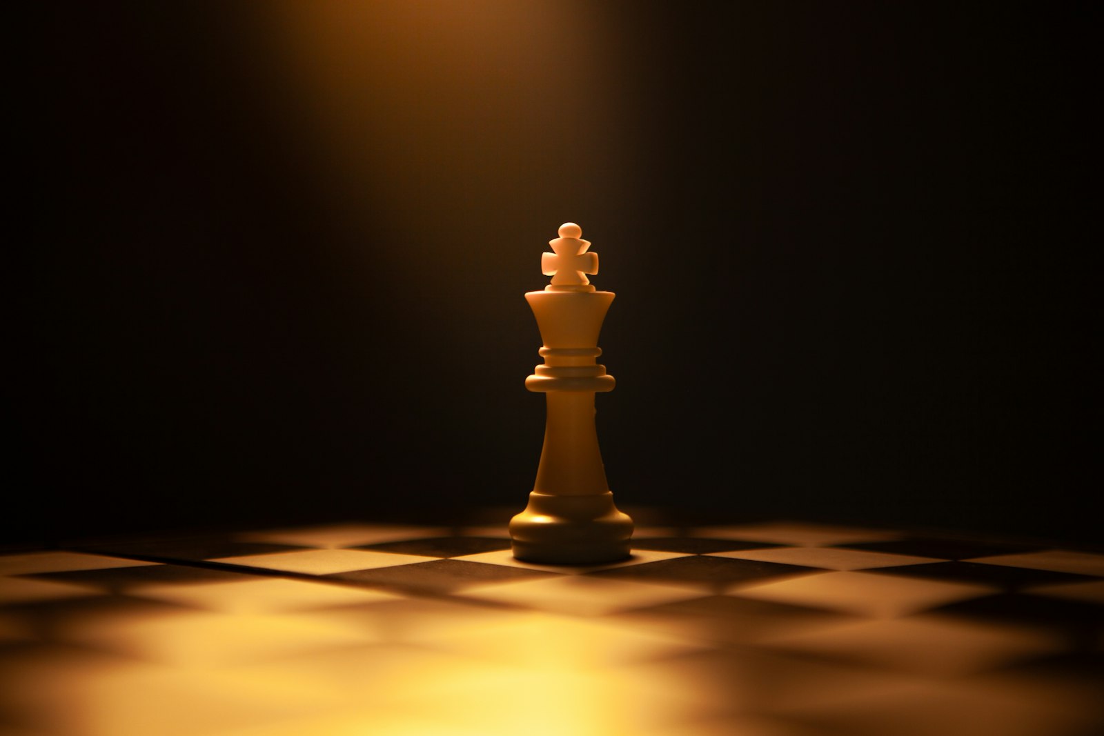 A lone white king chess piece standing alone against a dark background